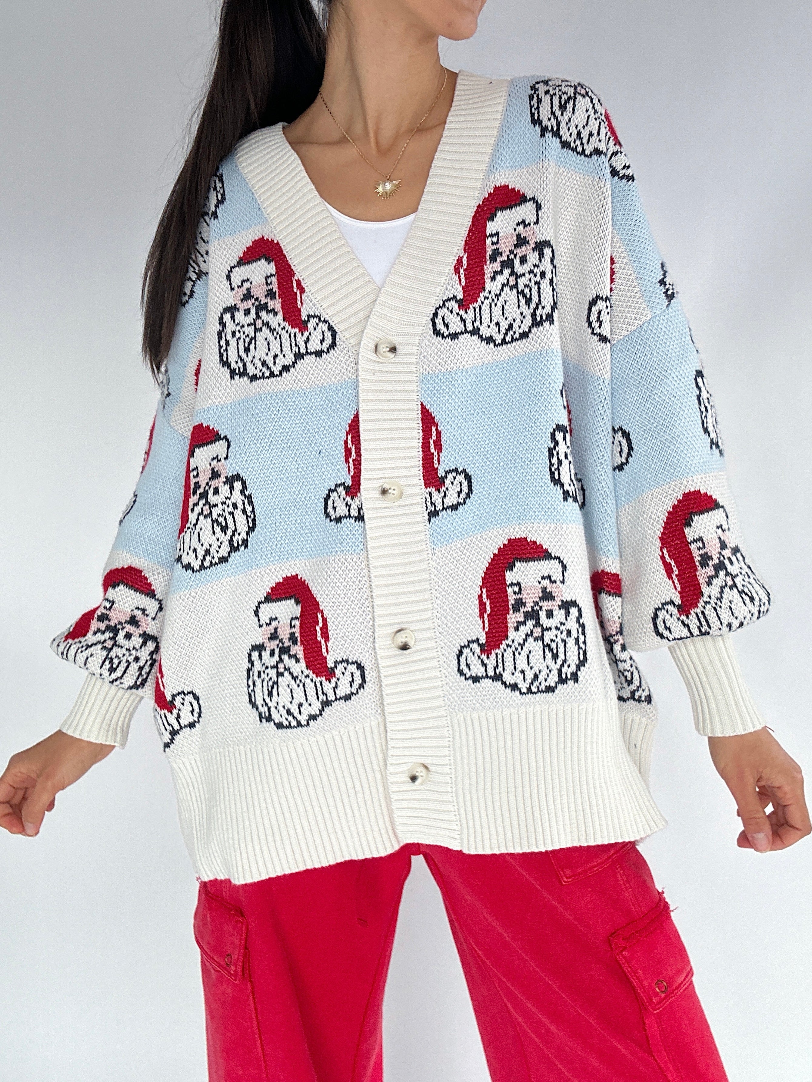 Person wearing a sweater with Santa Claus pattern on a plain background