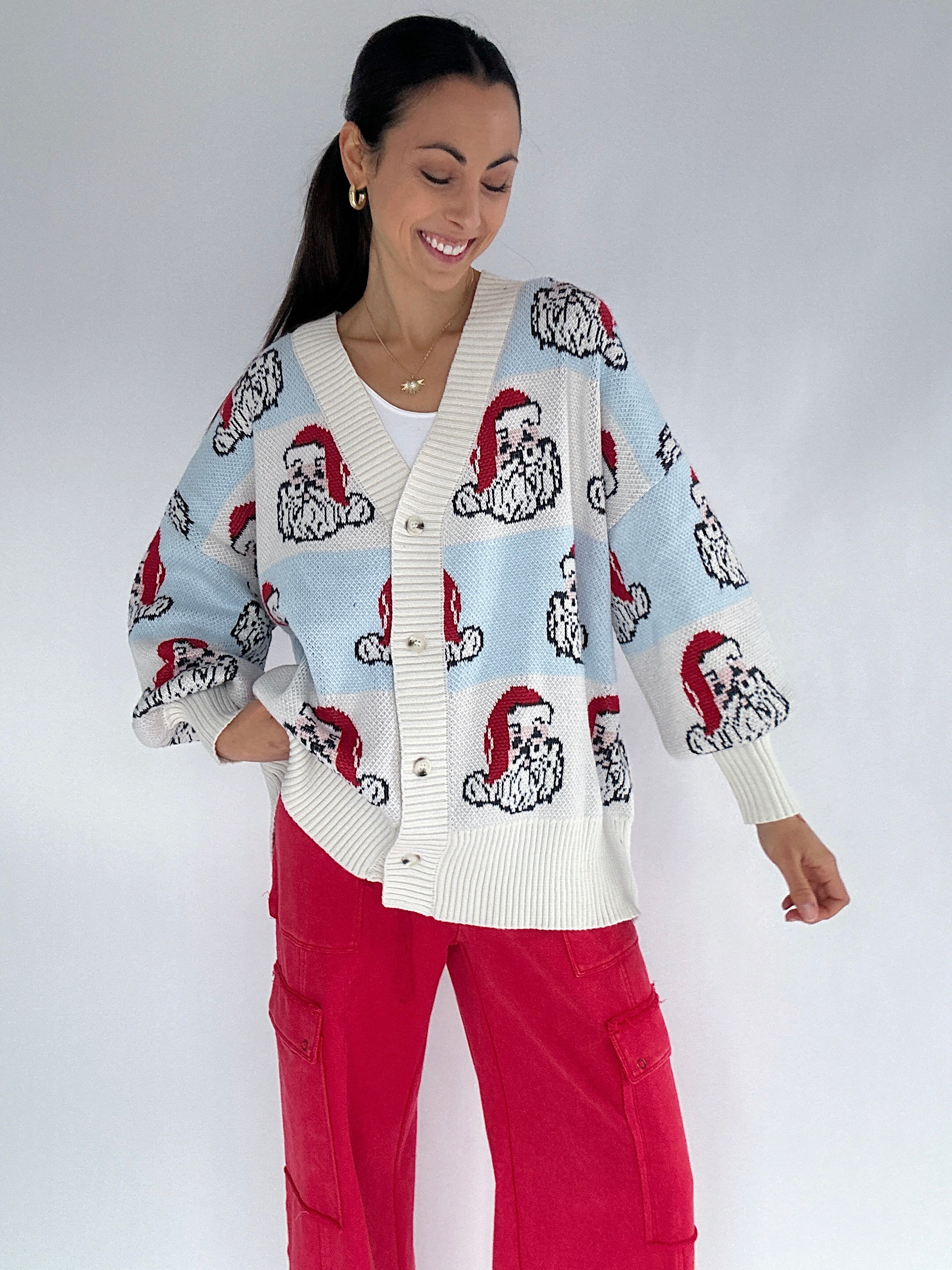Woman wearing a Santa face patterned cardigan with a white background