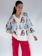 Woman wearing a Santa face patterned cardigan with a white background