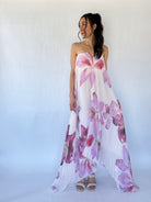 Woman wearing a strapless floral dress with pink and purple flowers on a white background