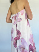Woman wearing a strapless floral dress with a blurred background showing the back zipper detail