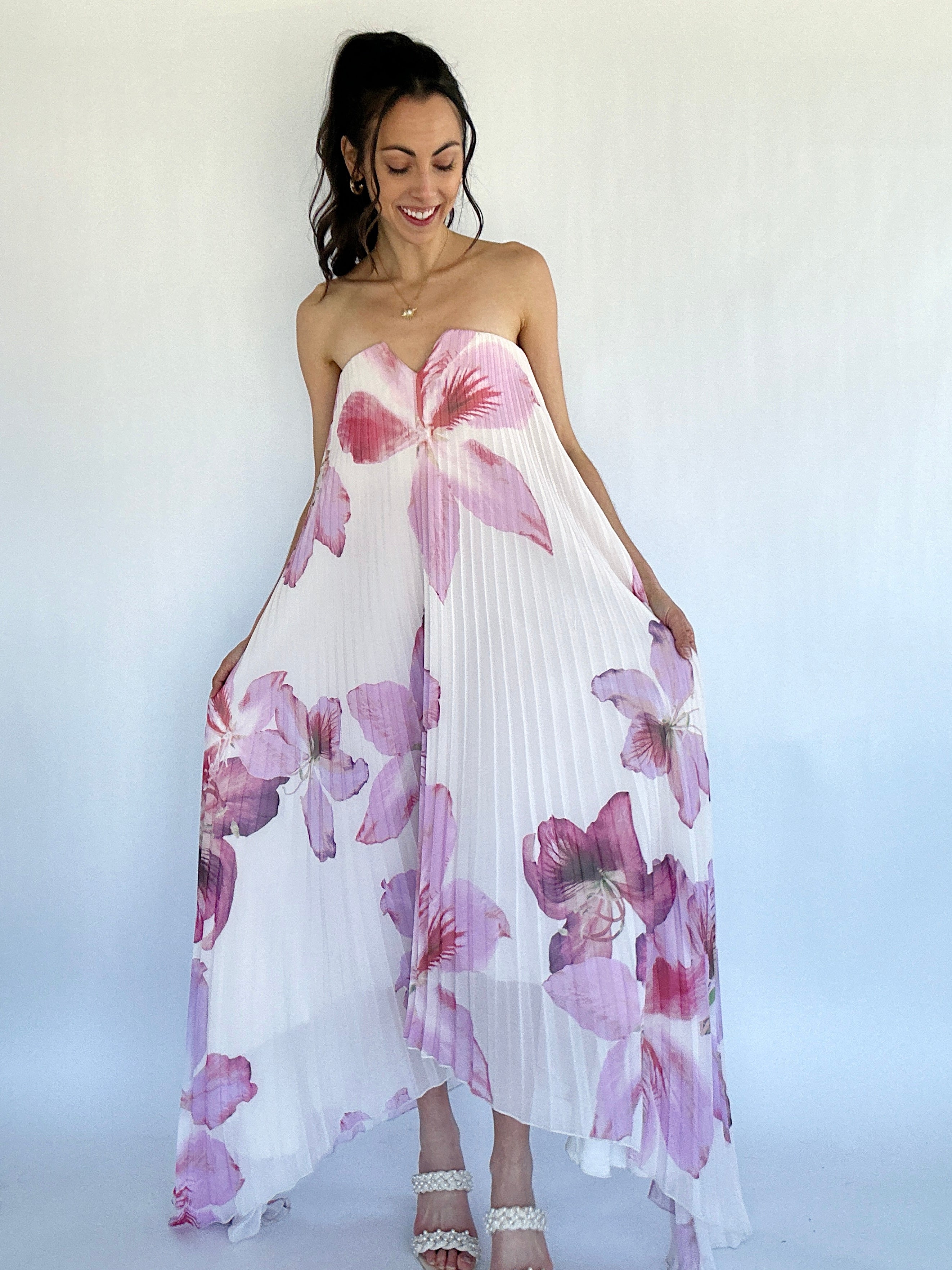 Woman wearing a strapless floral dress with pink and purple flowers on a white background