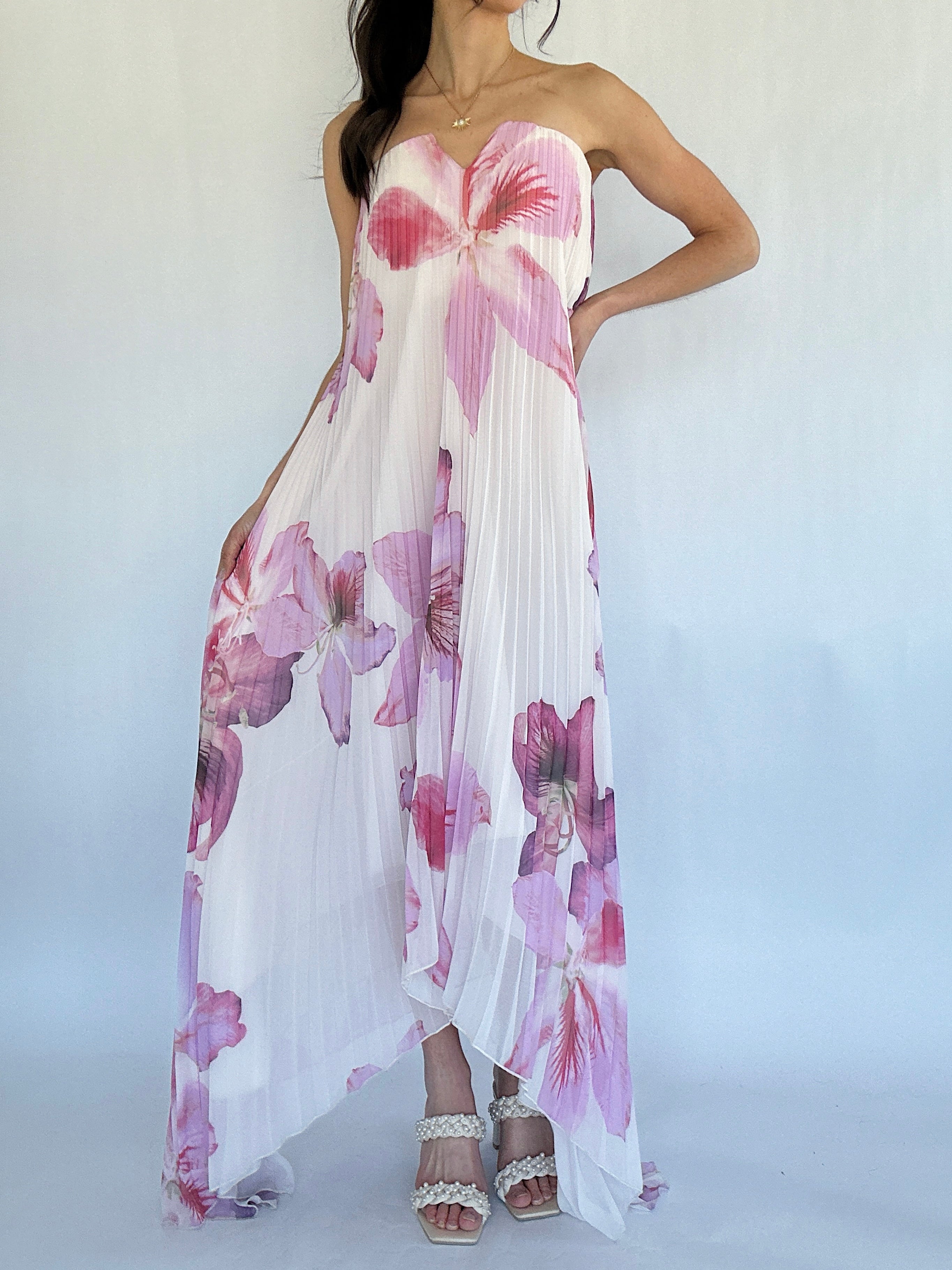 Woman wearing a strapless floral dress with pink and purple flowers on a white background