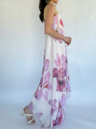 Woman wearing a floral dress with a white background from side