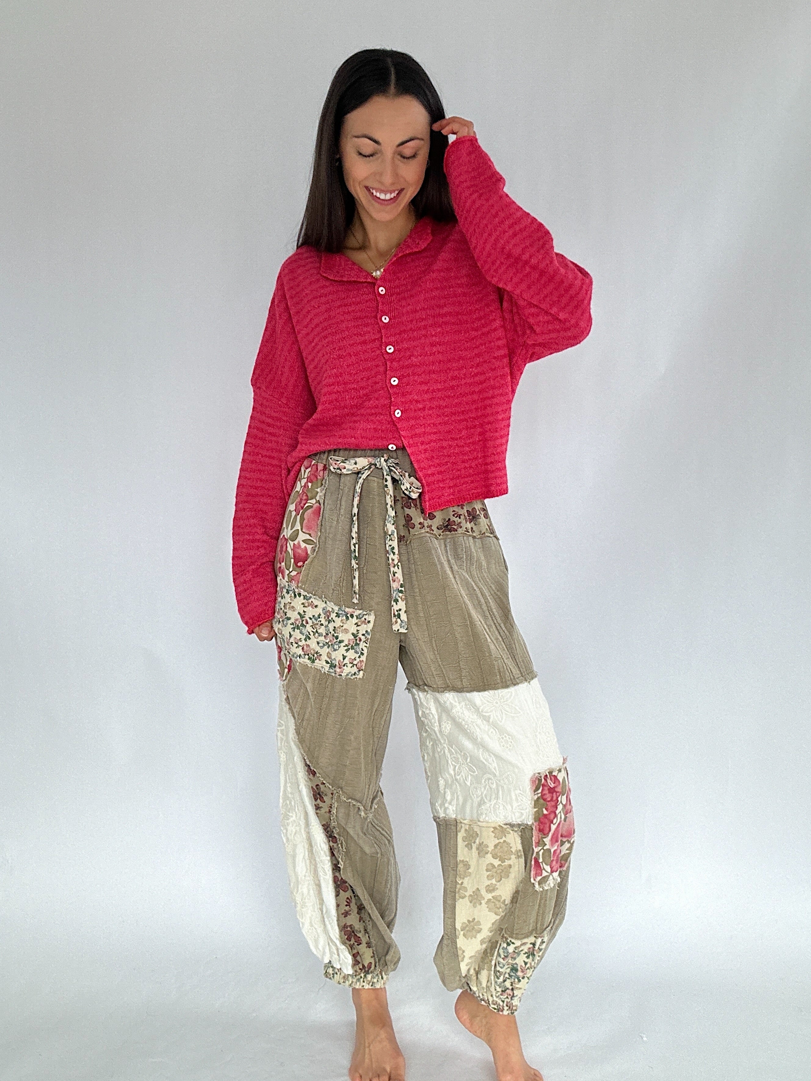 Woman wearing a red cardigan and floral patchwork pants on a white background
