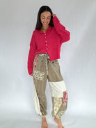 Woman wearing a red cardigan and floral patchwork pants on a white background