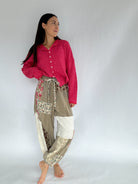 Woman wearing a pink sweater and patterned pants on a plain background