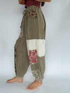 Patchwork harem pants with floral and solid patterns on a white background from side