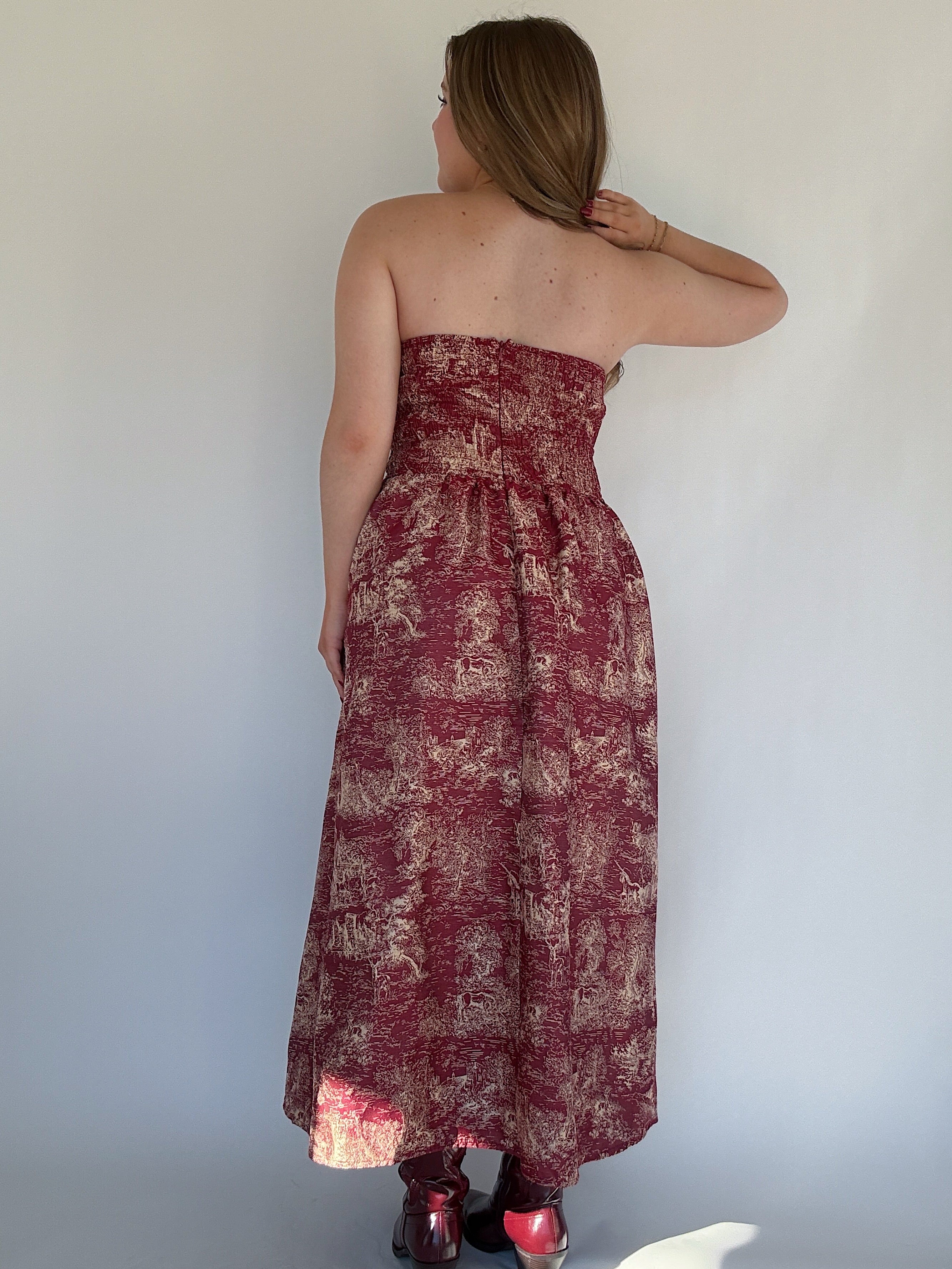 Woman wearing a strapless dress with a floral toile pattern against a plain background showing the back