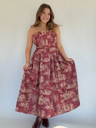 Woman wearing a strapless dress with a floral pattern against a plain background