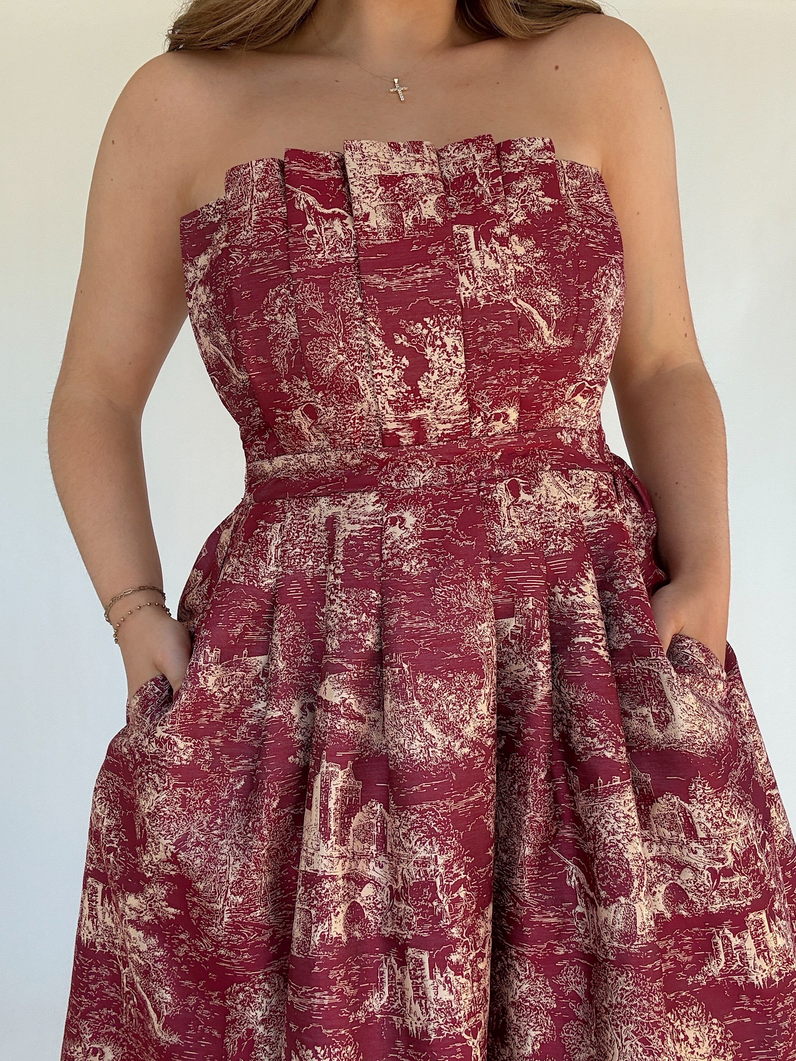 Red strapless dress with a toile pattern on a white background showing top and pockets