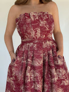 Red strapless dress with a toile pattern on a white background showing top and pockets