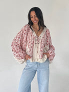 Woman wearing a floral blouse and light blue jeans against a plain background