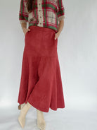 Person wearing a red plaid sweater and red suede skirt on a white background