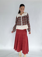 Woman wearing a plaid shirt with lace details and a red skirt on a white background
