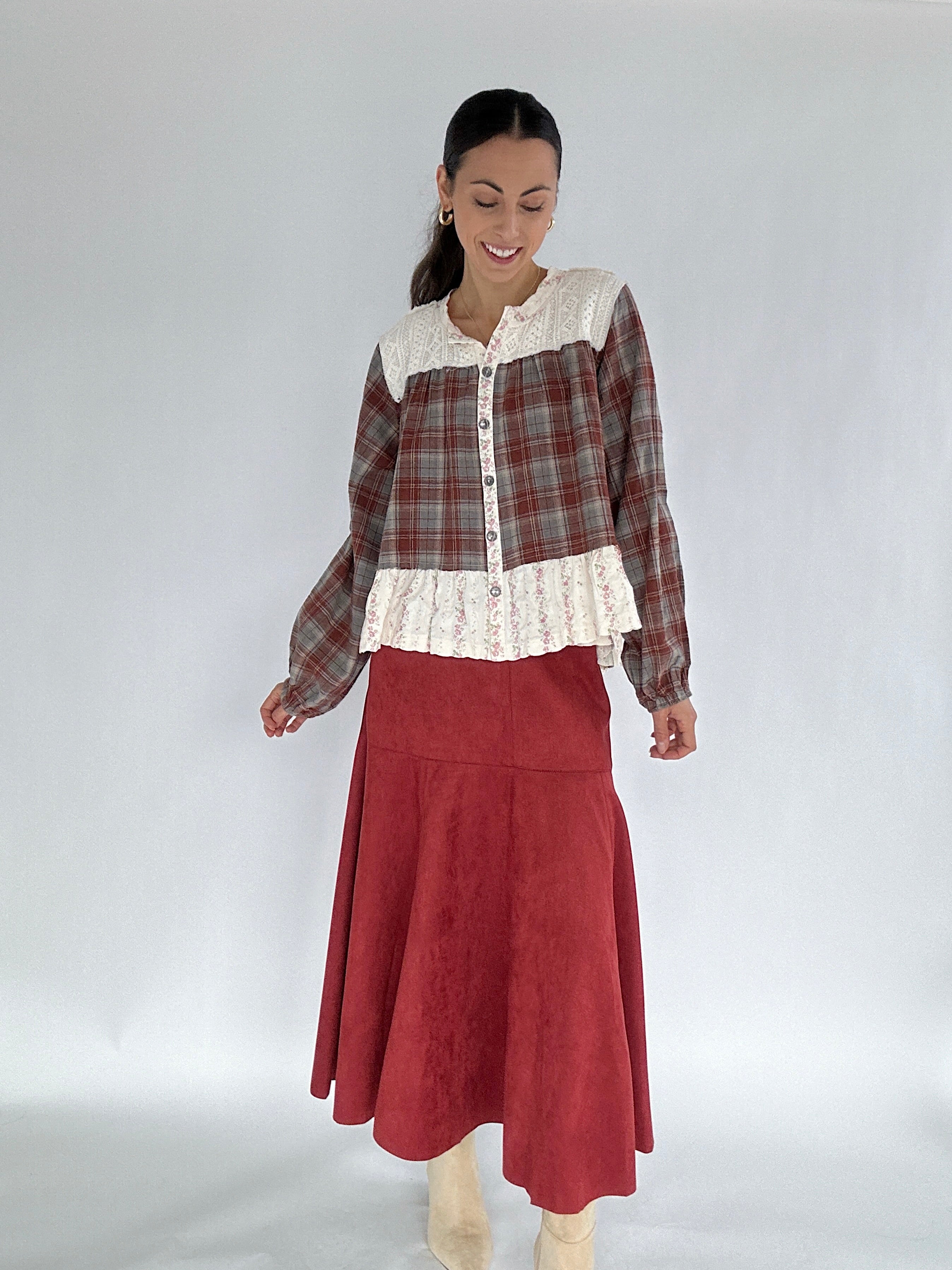 Woman wearing a plaid shirt with lace details and a red skirt on a white background