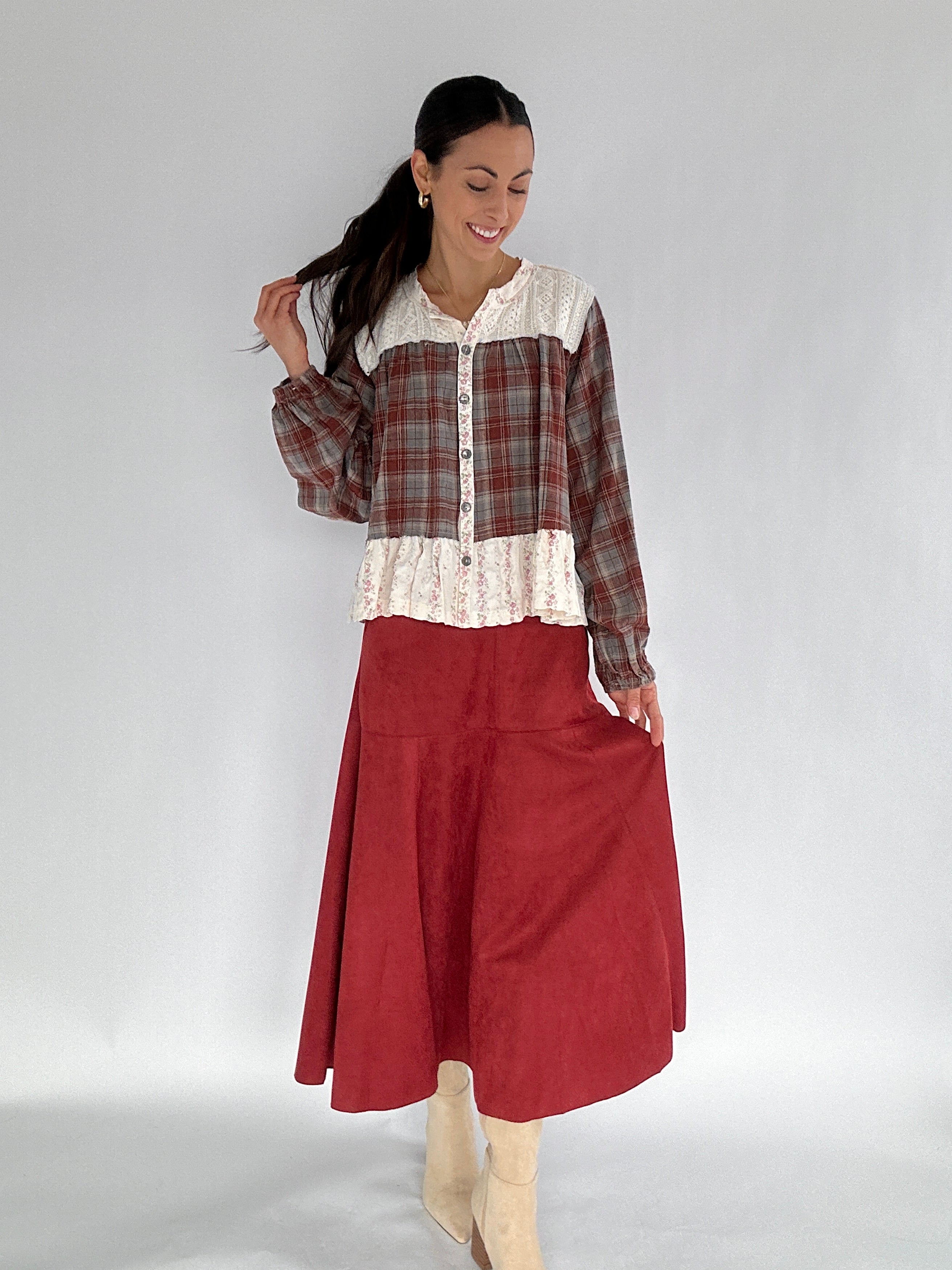 Woman wearing a plaid shirt and red skirt on a white background