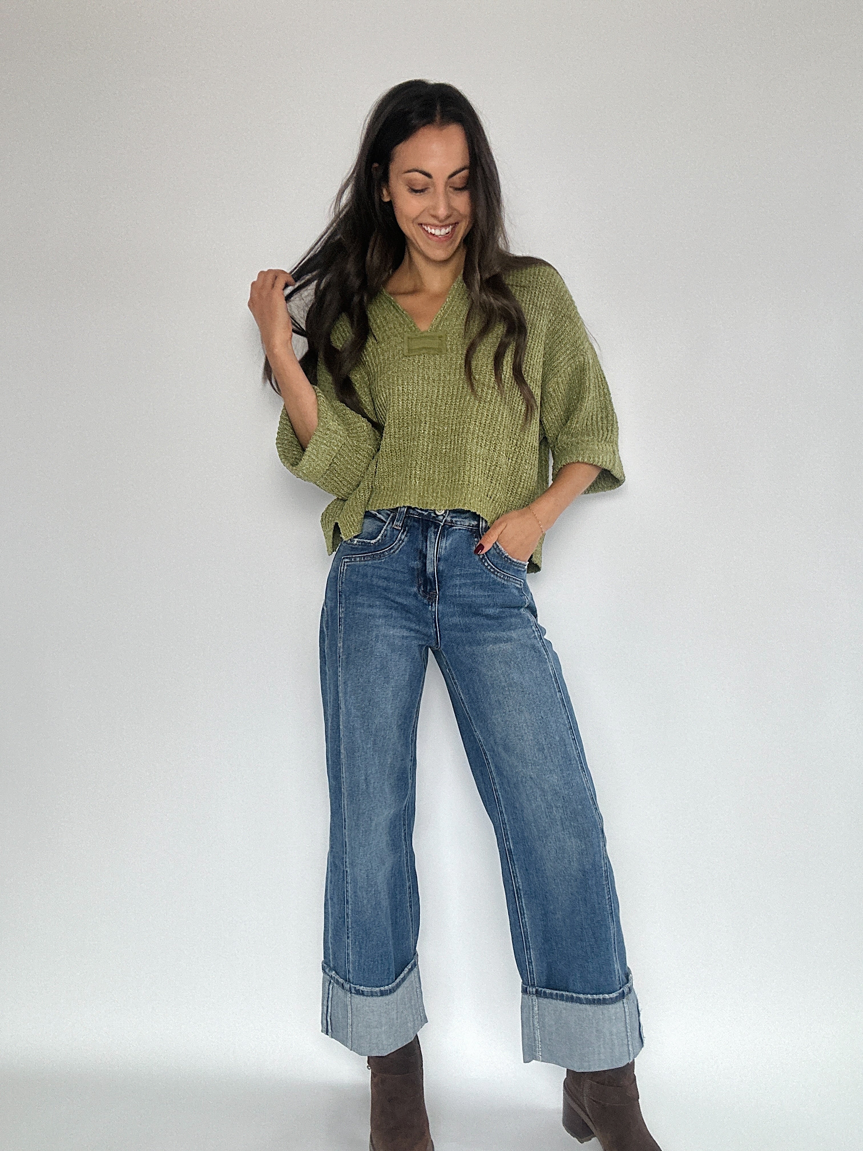 Woman wearing medium wash cufffed wide leg jeans and green cropped sweater top.