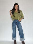 Woman wearing medium wash cufffed wide leg jeans and green cropped sweater top.