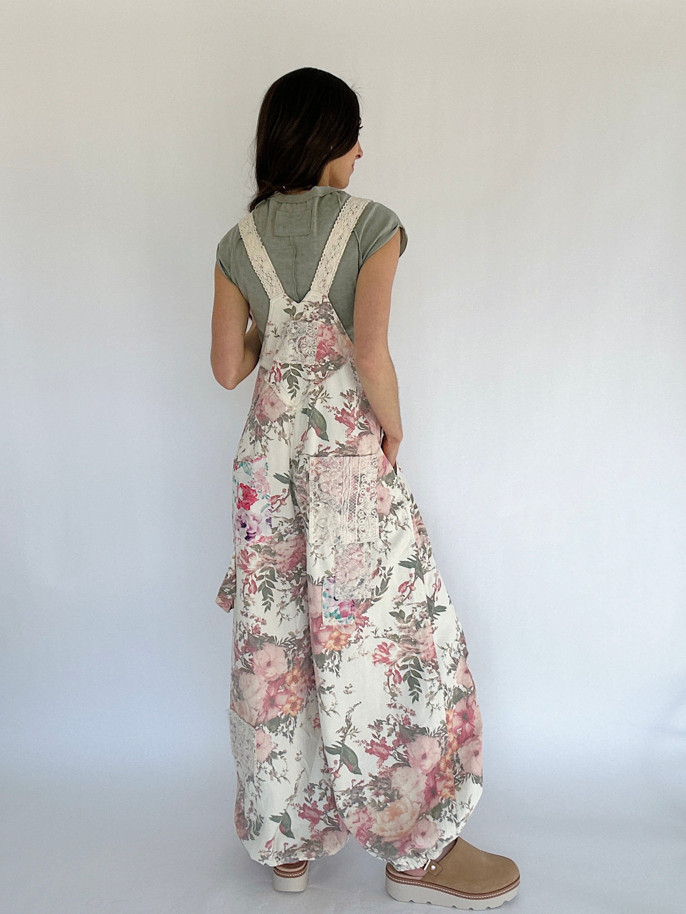 Person wearing floral overalls with a plain background showing the back
