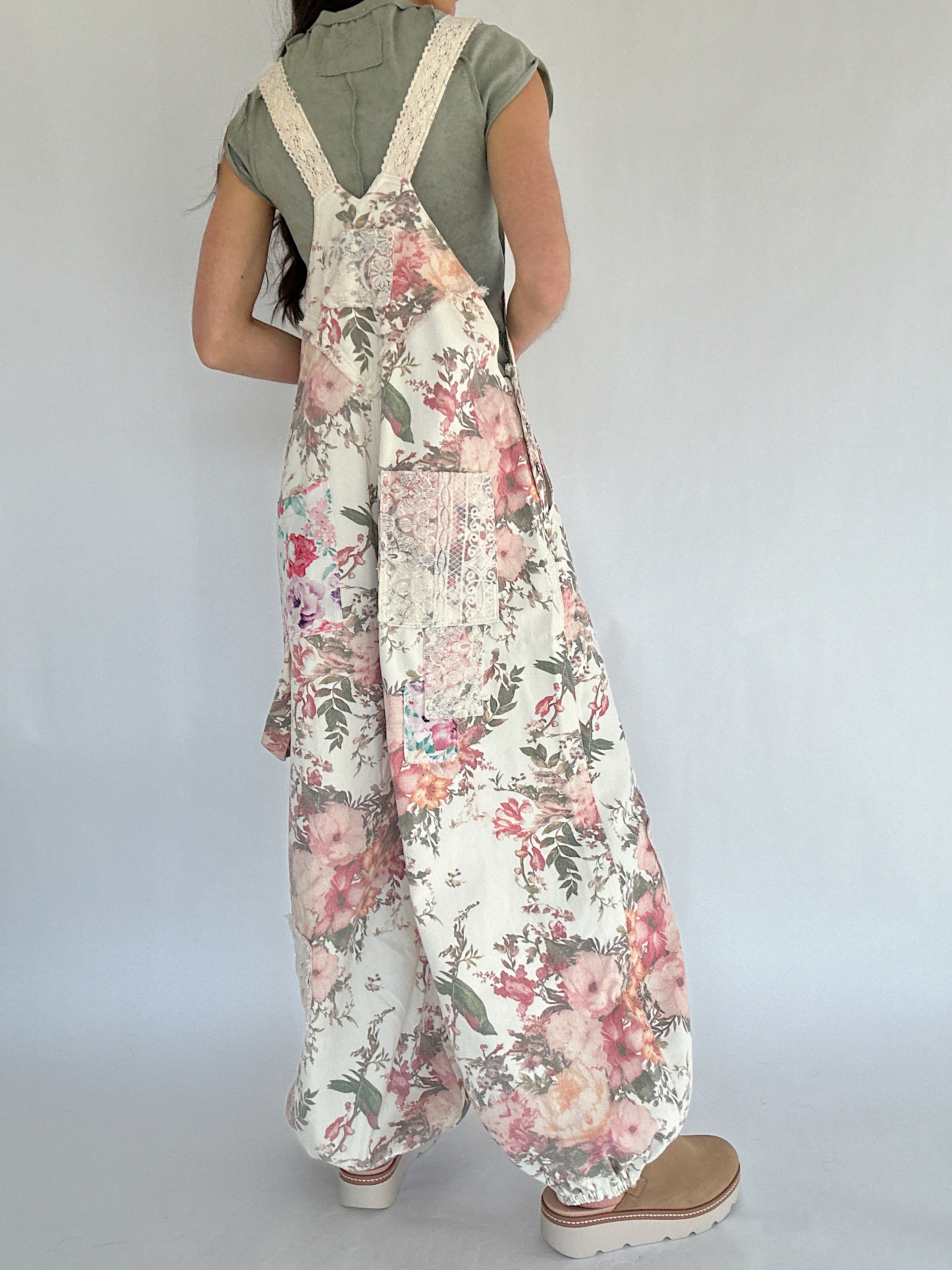 Person wearing a floral overalls with a plain background from back