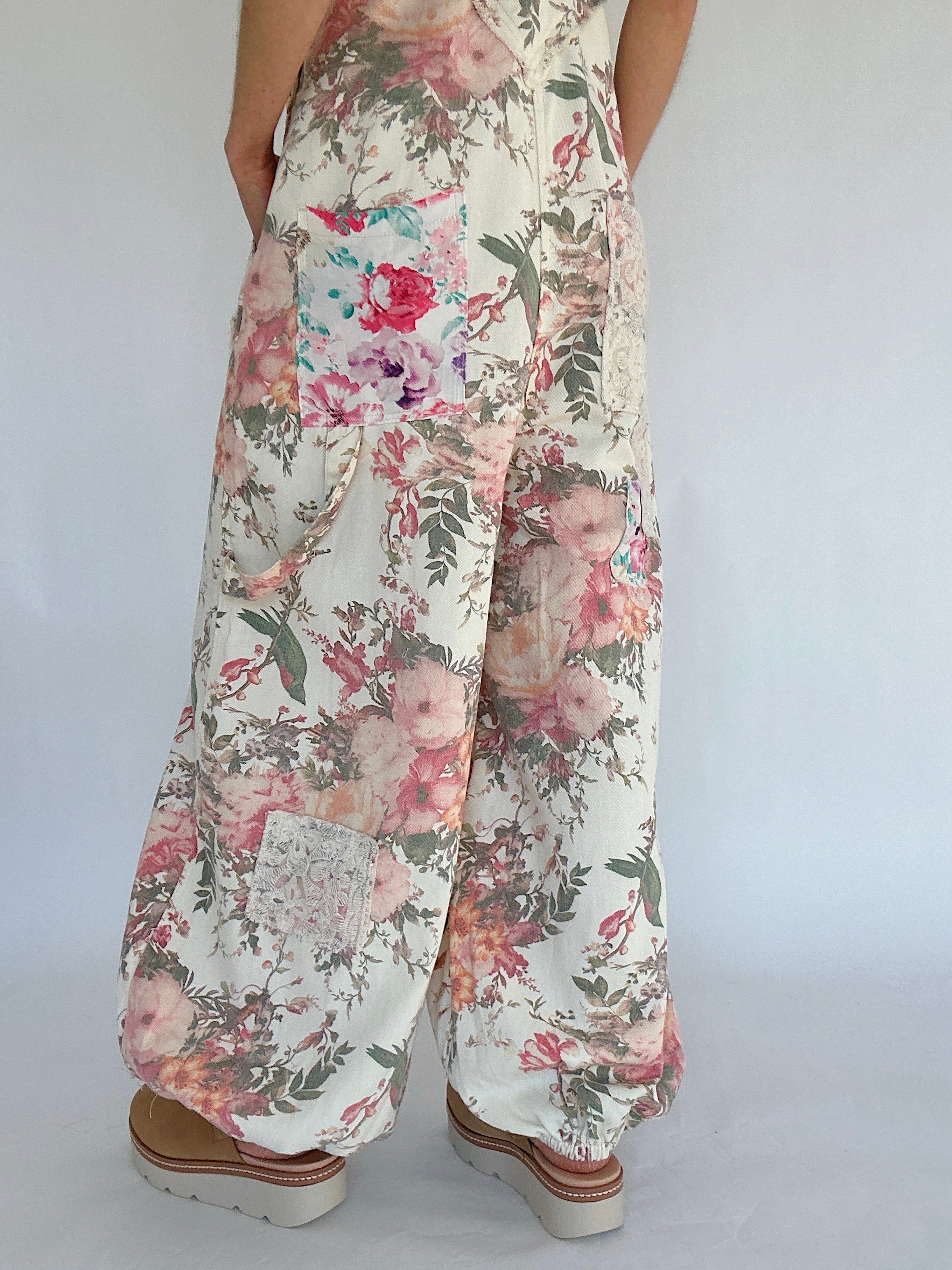 Floral patterned overalls worn by a person on a white background showing leg details