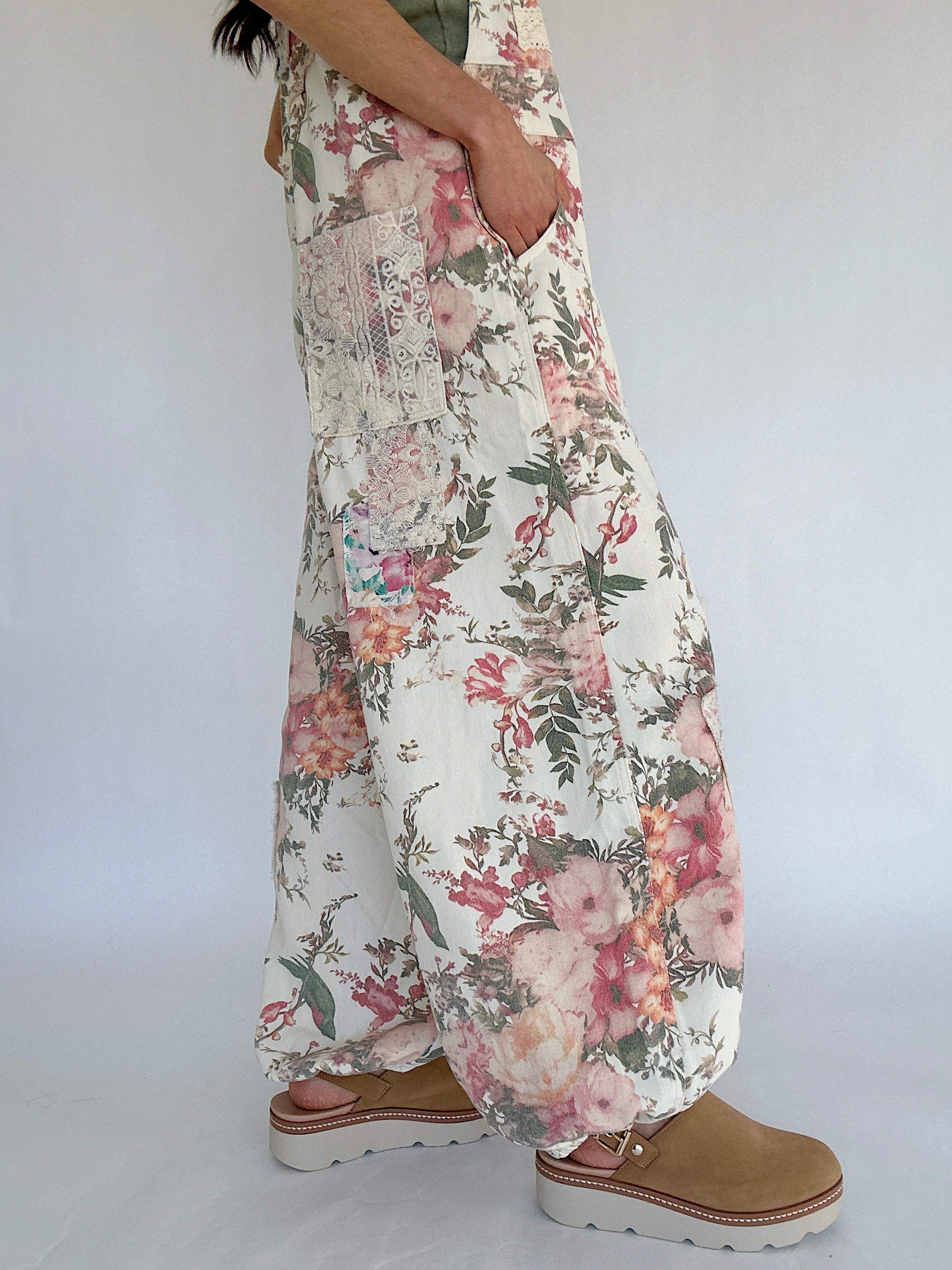 Floral patterned overalls worn by a person on a plain background showing side pockets