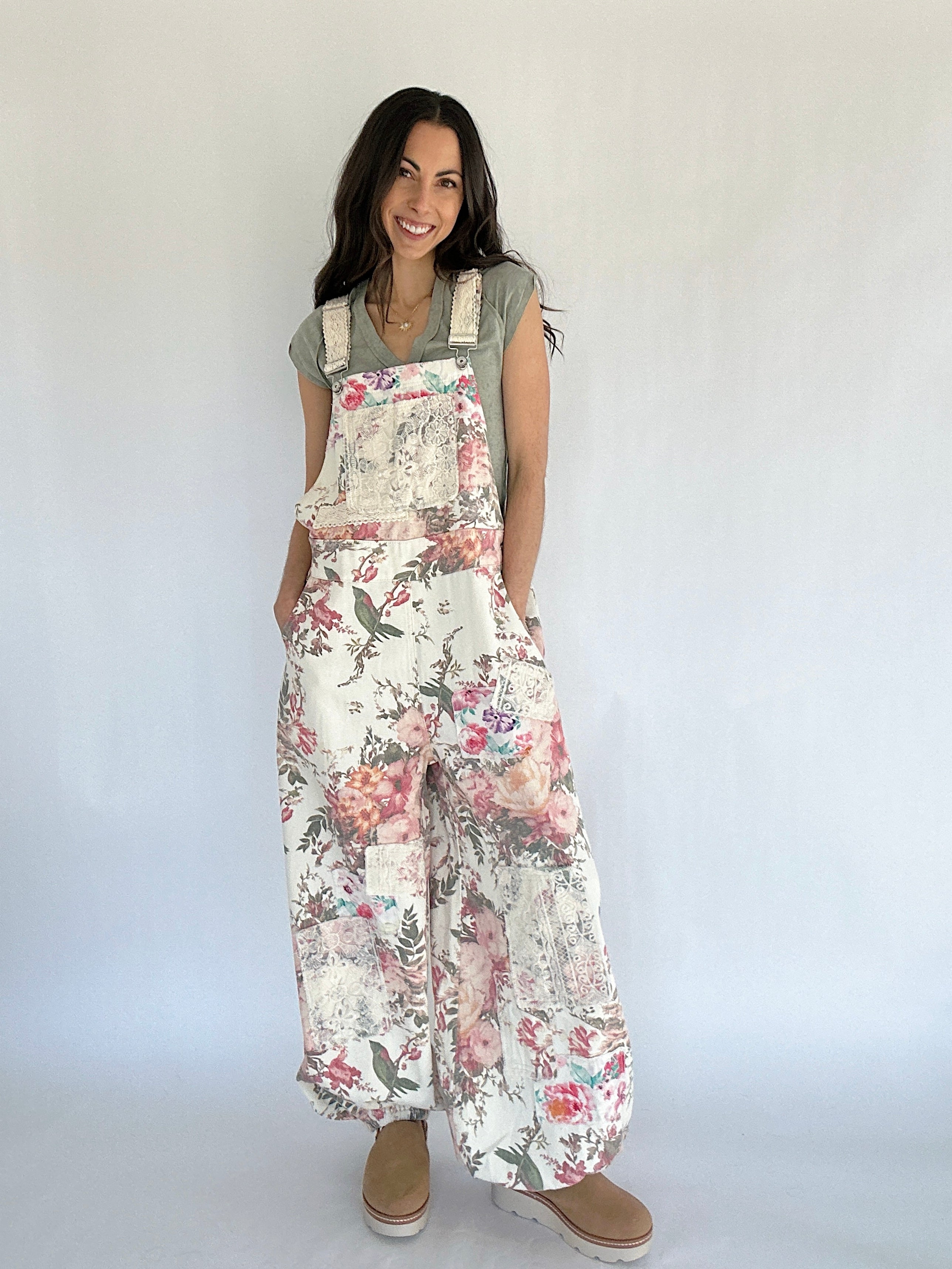 Woman wearing floral overalls against a plain background