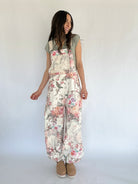Woman wearing floral overalls against a white background