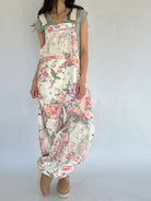 Person wearing floral overalls with a baggy silhouette on a plain background