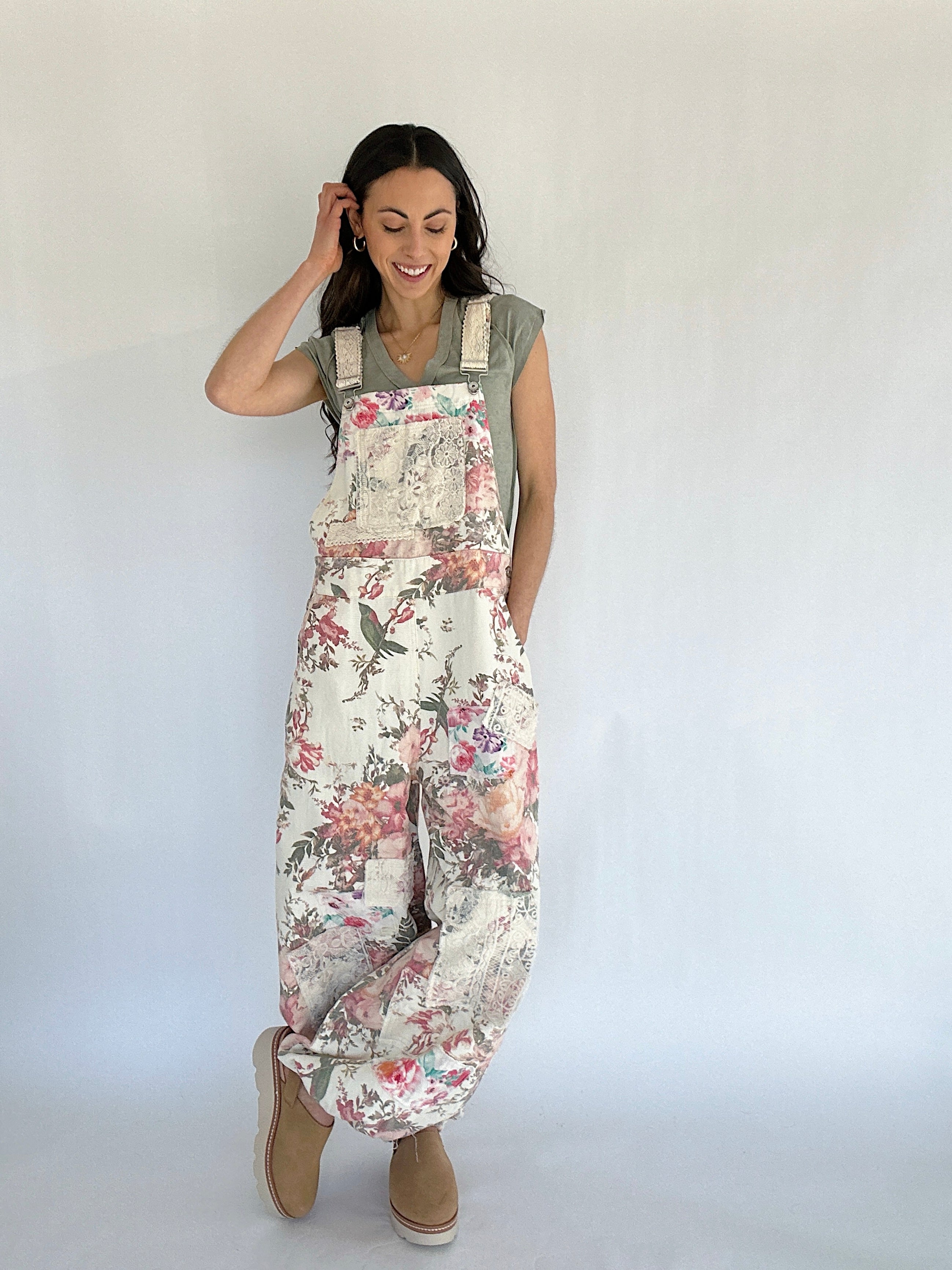 Woman wearing floral overalls against a plain background