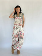 Woman wearing floral overalls against a plain background