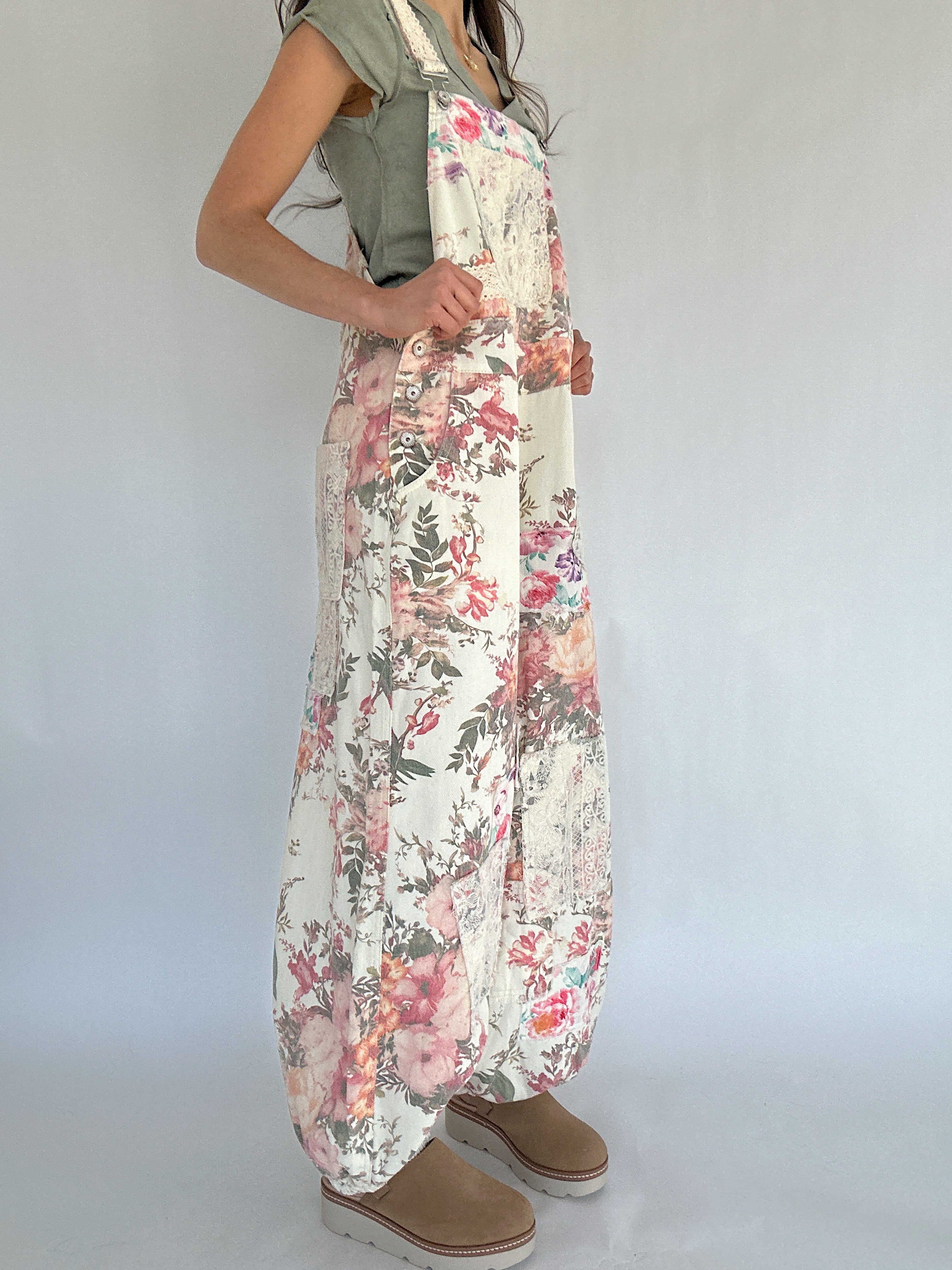 Person wearing floral overalls on a plain background from side