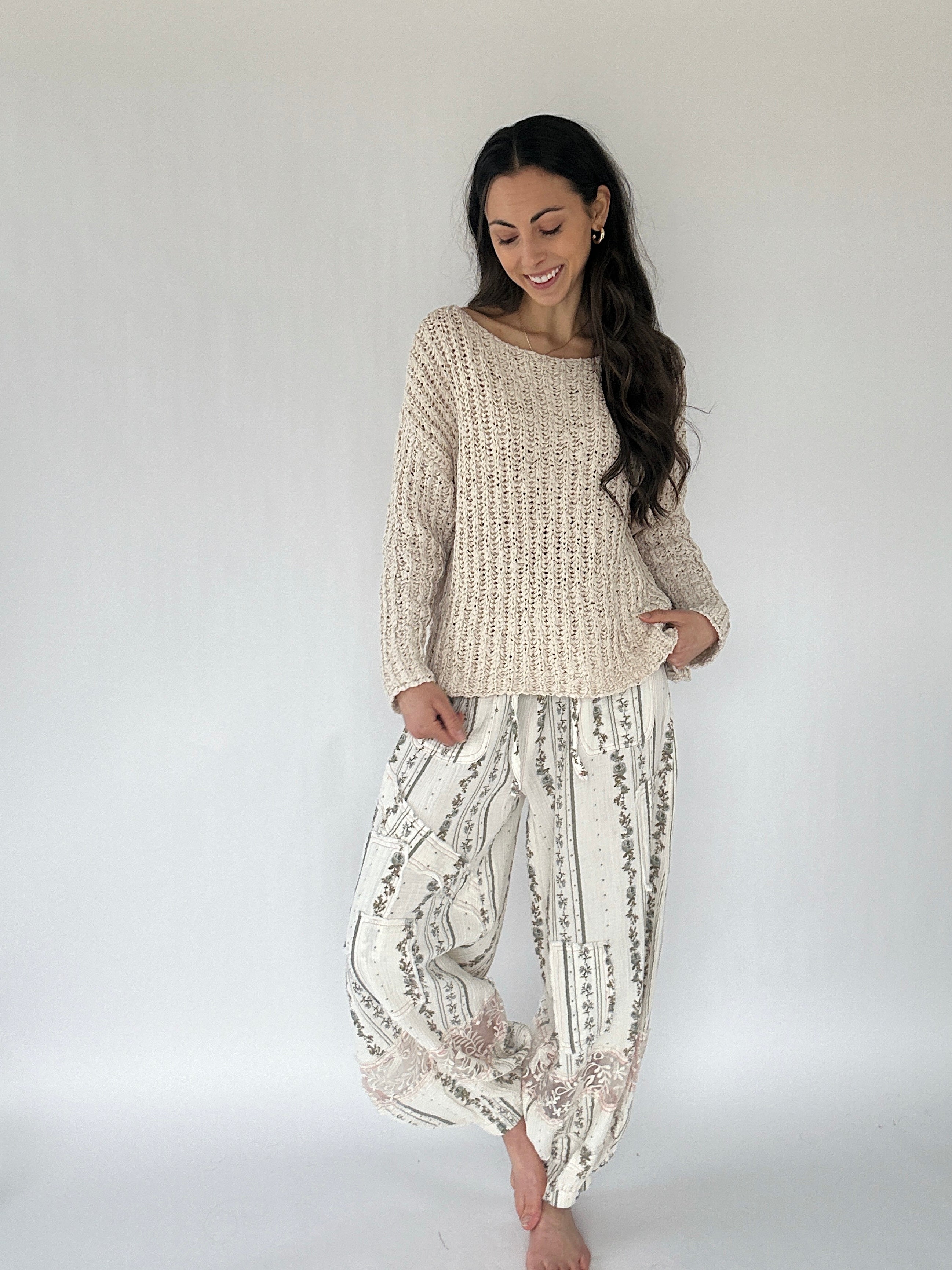Woman wearing a textured sweater and patterned pants against a white background