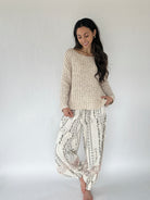 Woman wearing a textured sweater and patterned pants against a white background