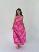 Woman wearing a pink dress with red stripes on a white background