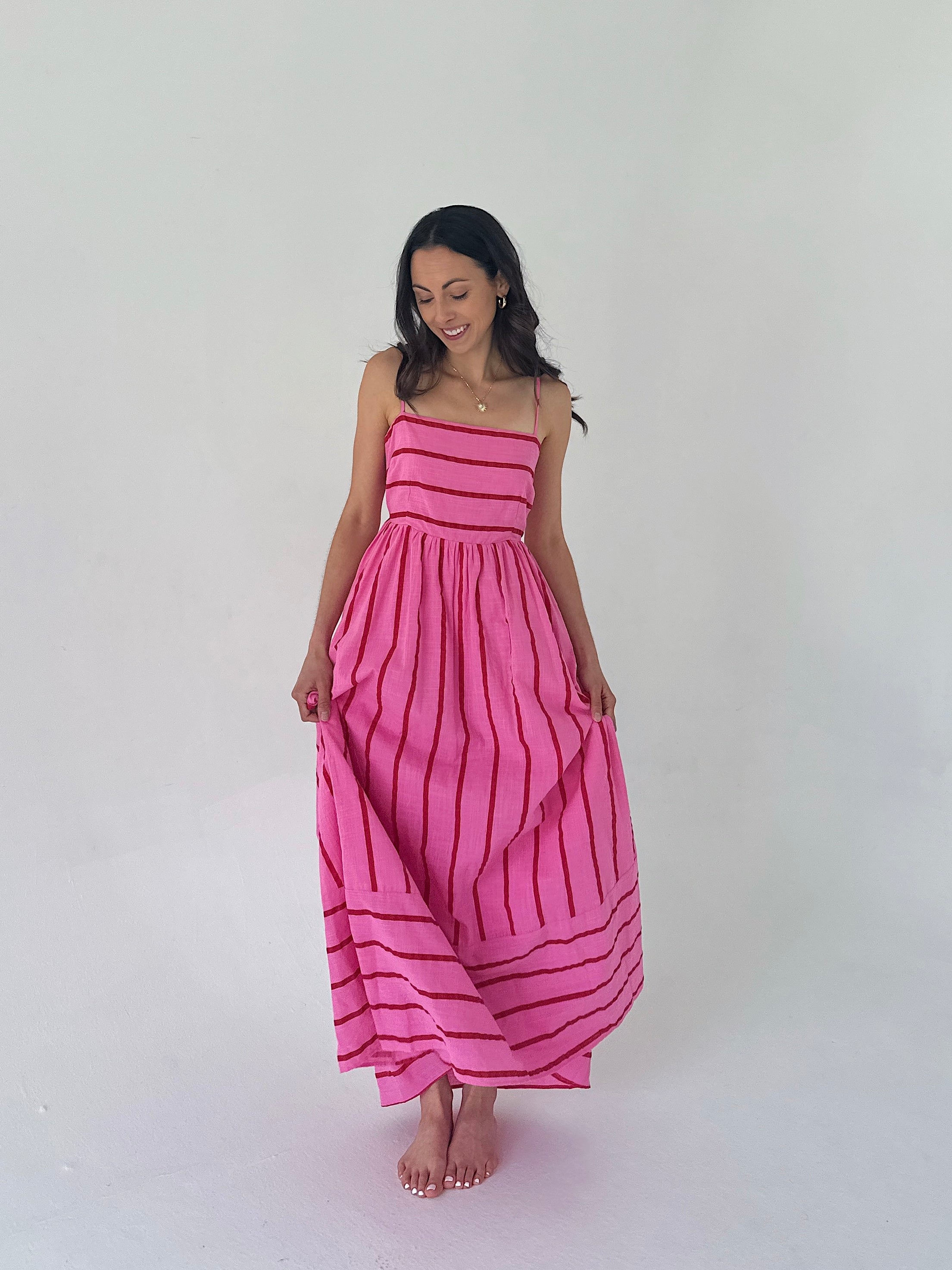Woman wearing a pink dress with red stripes on a white background