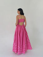 Woman wearing a pink dress with back cut-out back on a white background