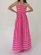 Woman wearing a pink dress with red stripes on a plain background