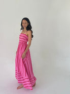 Woman wearing a pink dress against a white background from side