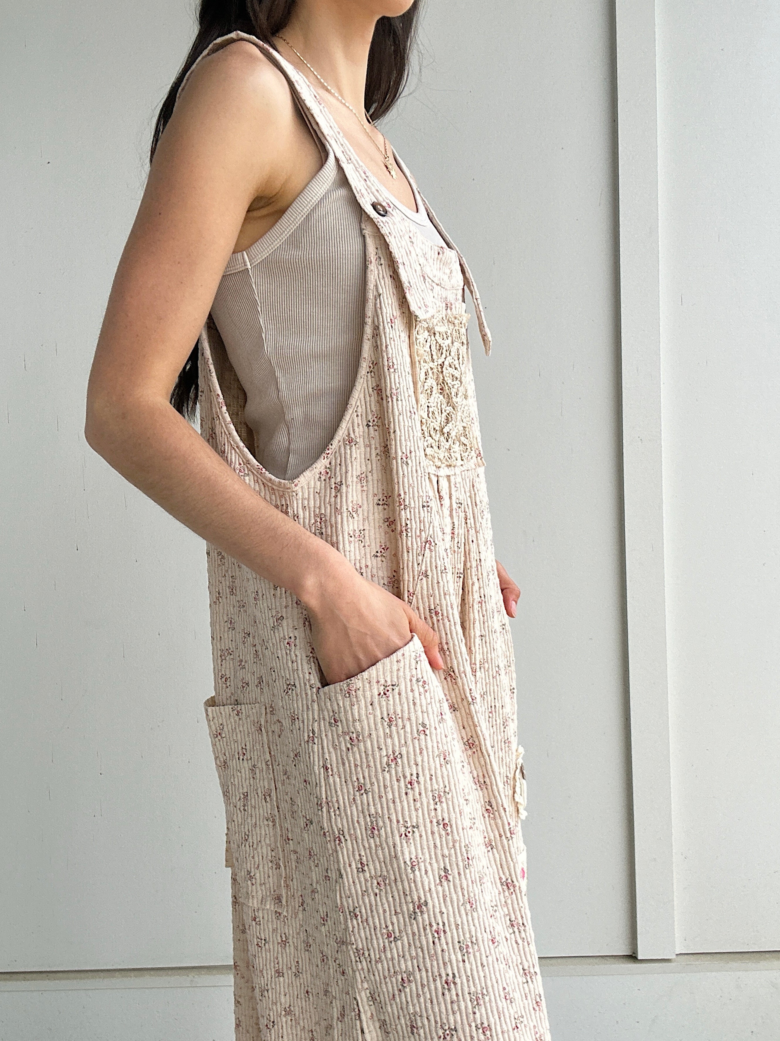 Person wearing a beige overalls with a plain background showing side pockets