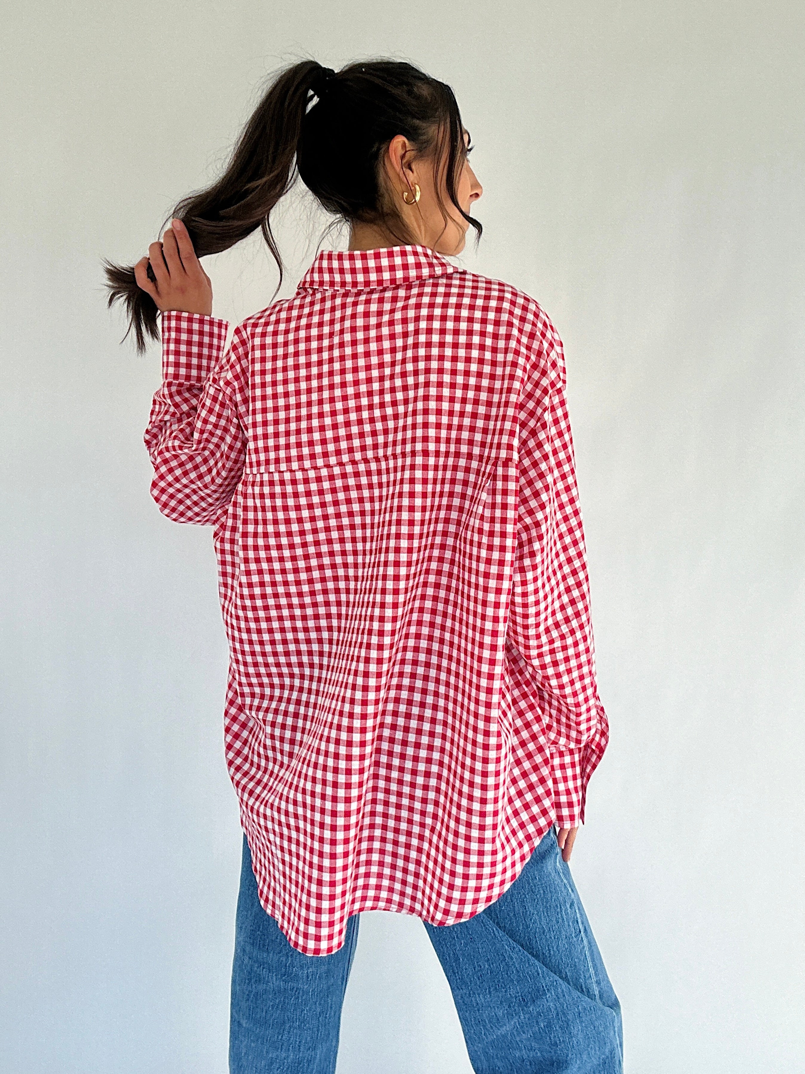 Person wearing a red and white checkered shirt against a plain background