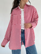 Person wearing a red and white checkered shirt over a white top with blue jeans on a plain background