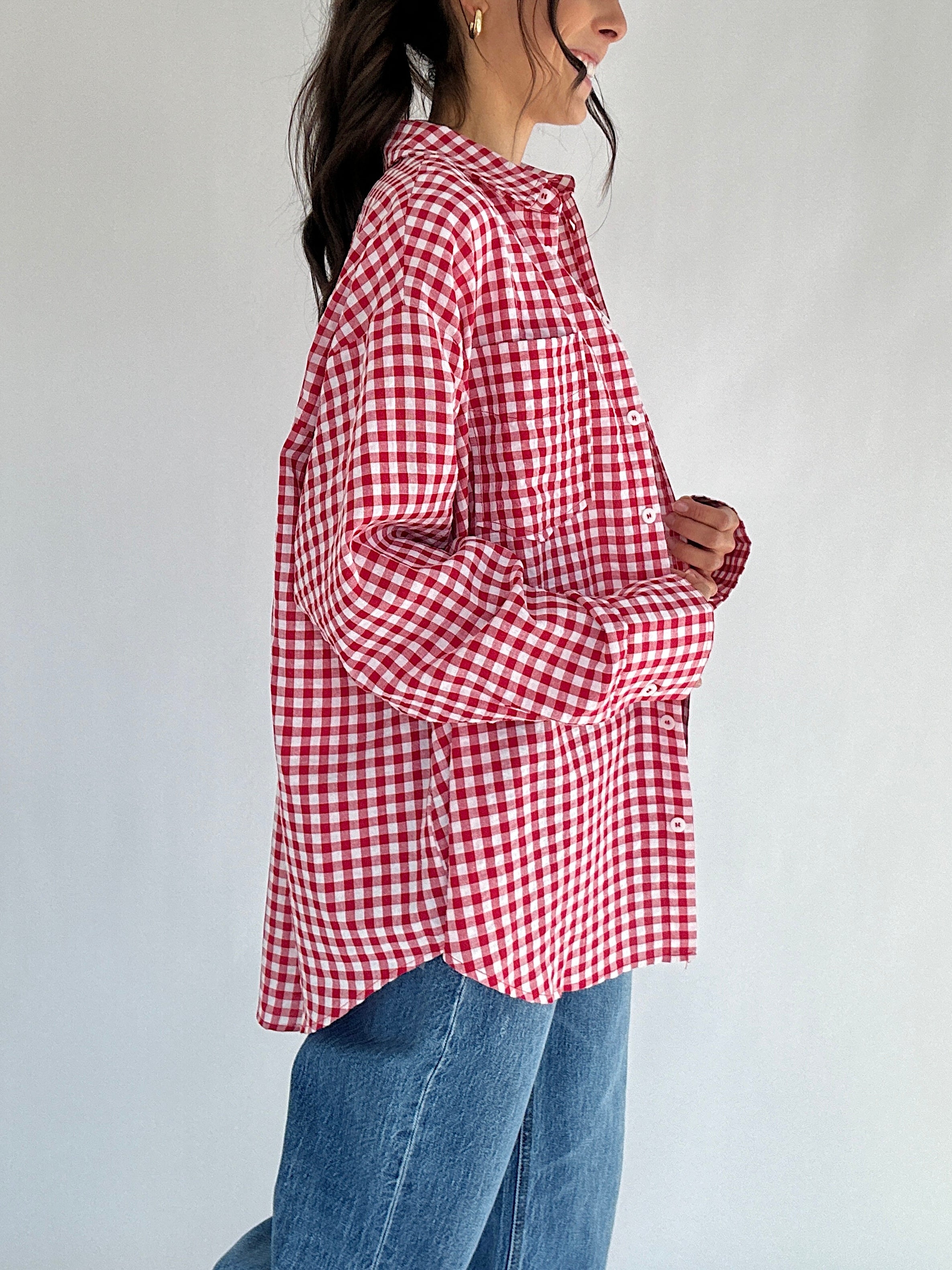 Person wearing a red and white checkered shirt with a plain background from side