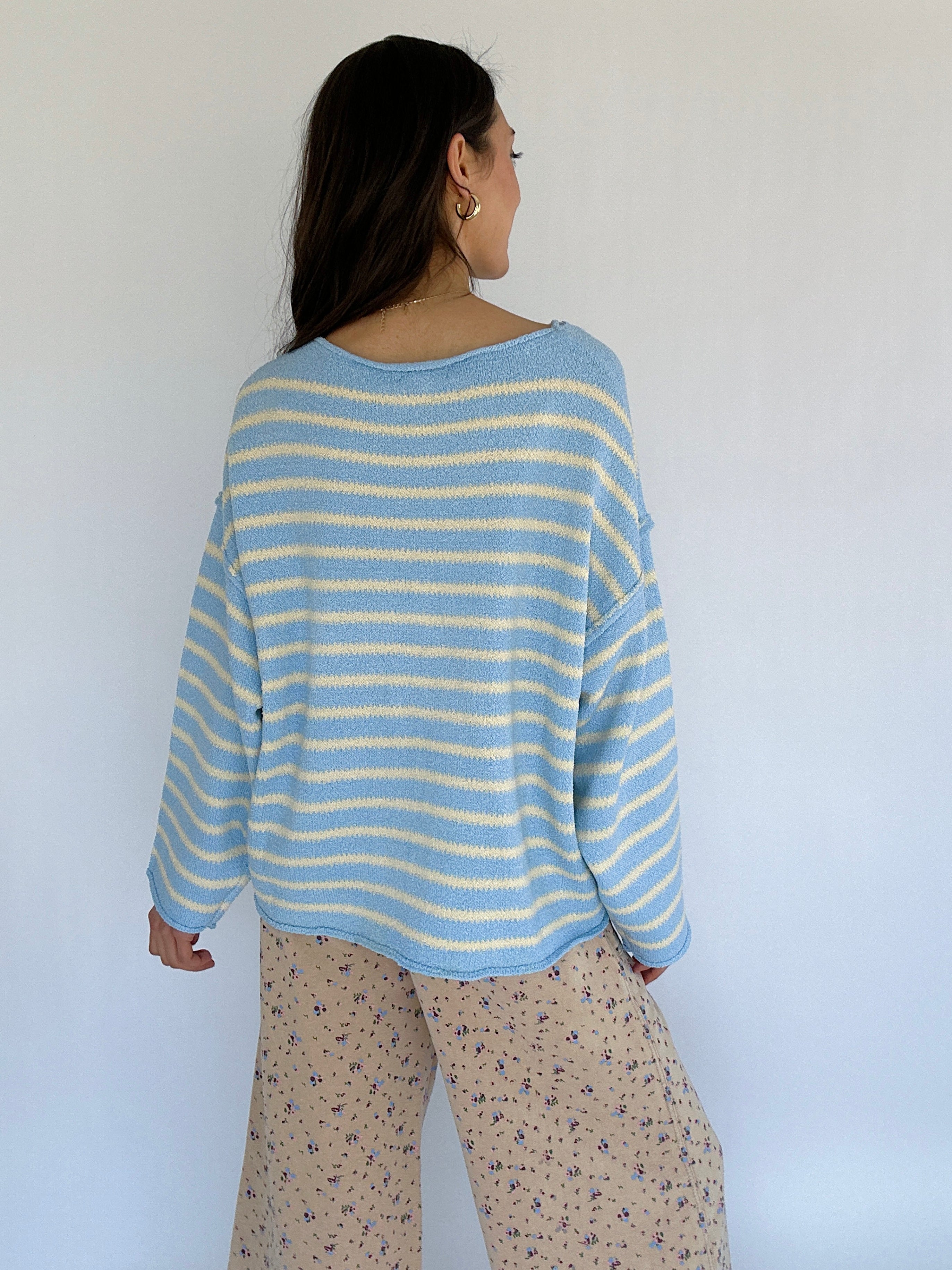 Person wearing a blue and white striped sweater against a white background