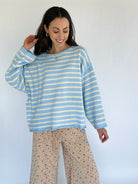 Woman wearing a blue and white striped sweater with patterned pants against a white background