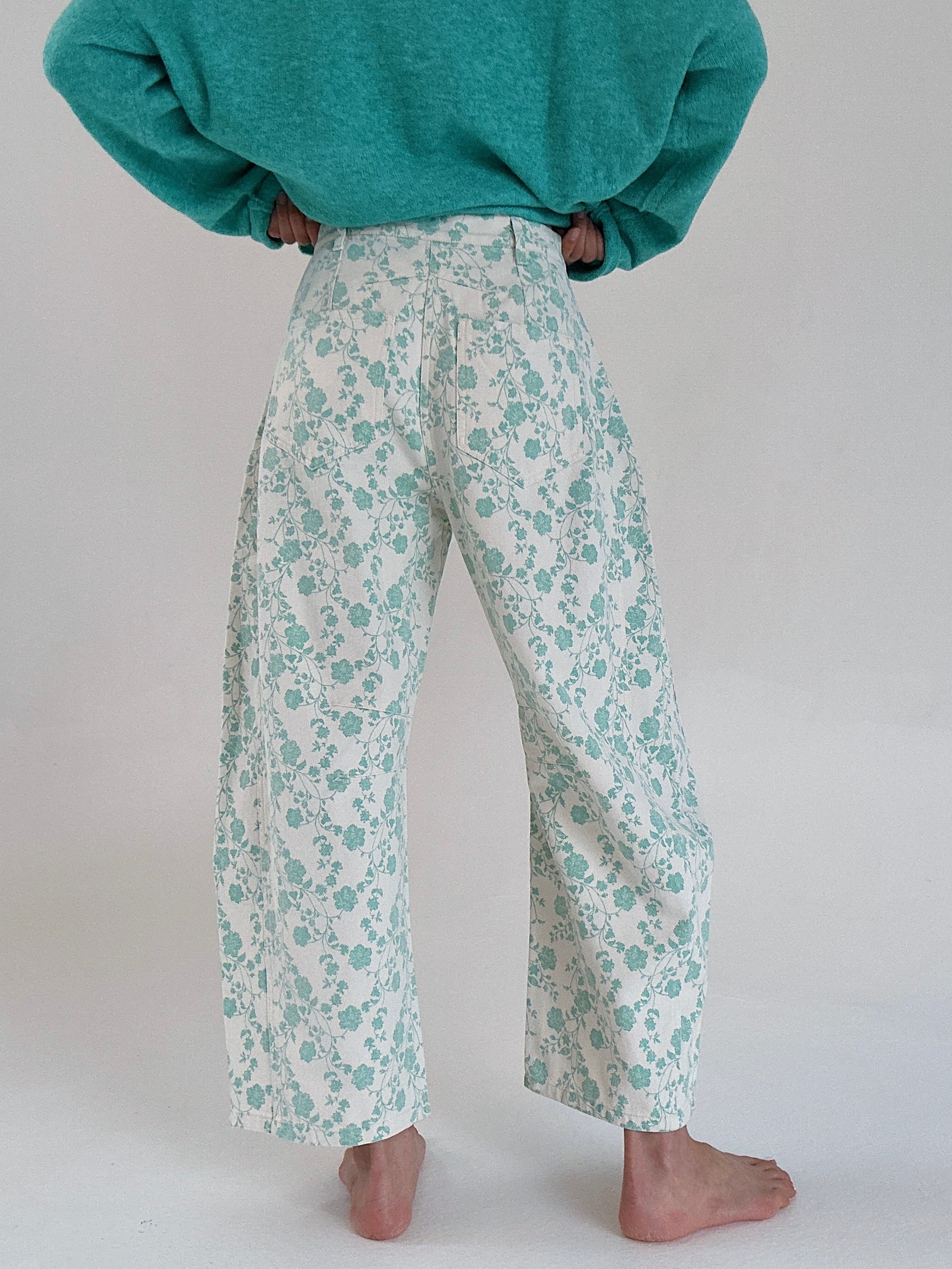 Person wearing teal floral pants and a matching top on a plain background from back