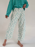 Person wearing teal floral pants and a matching cardigan on a white background