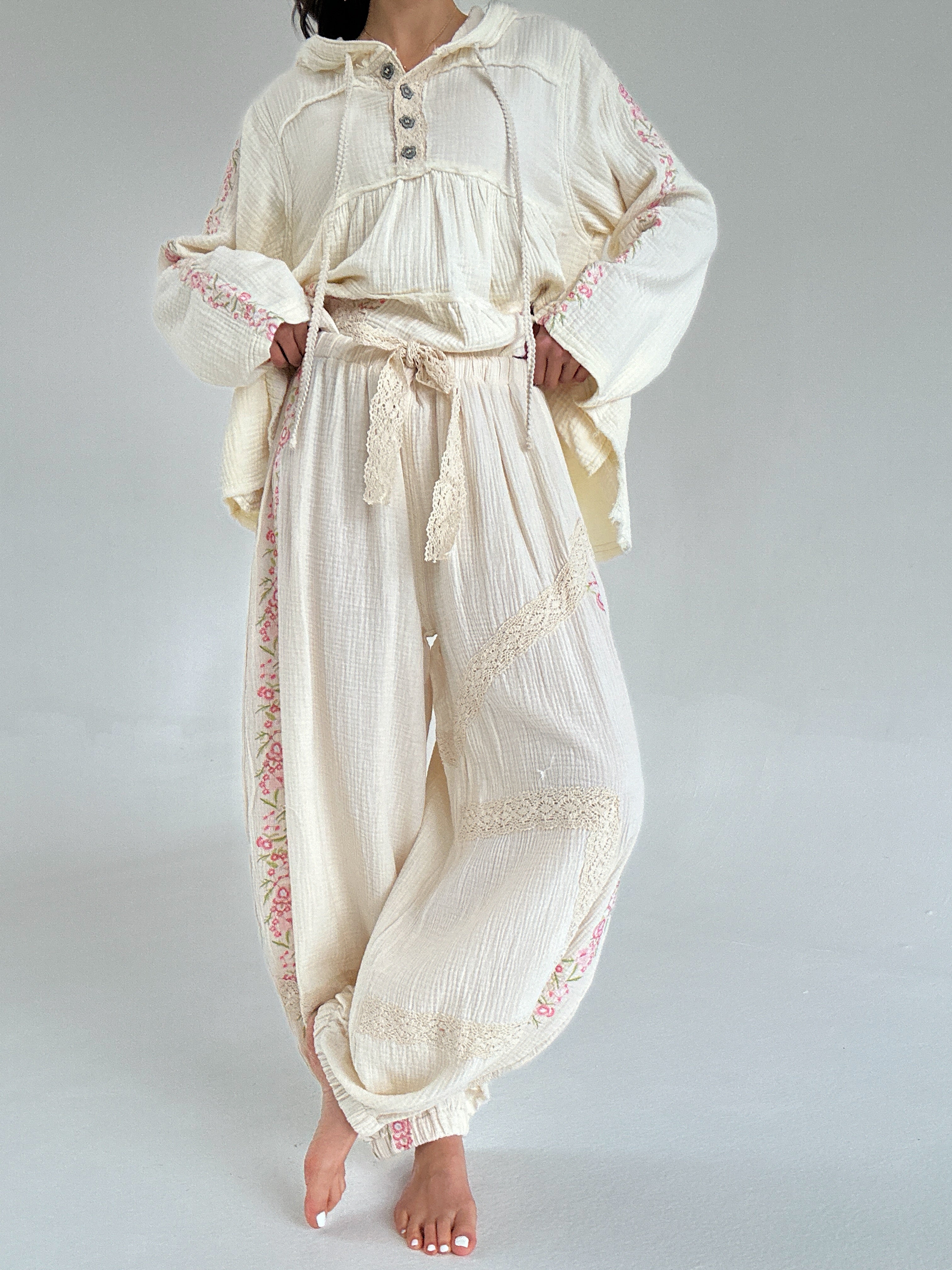 Person wearing a cream-colored outfit with lace details on a plain background