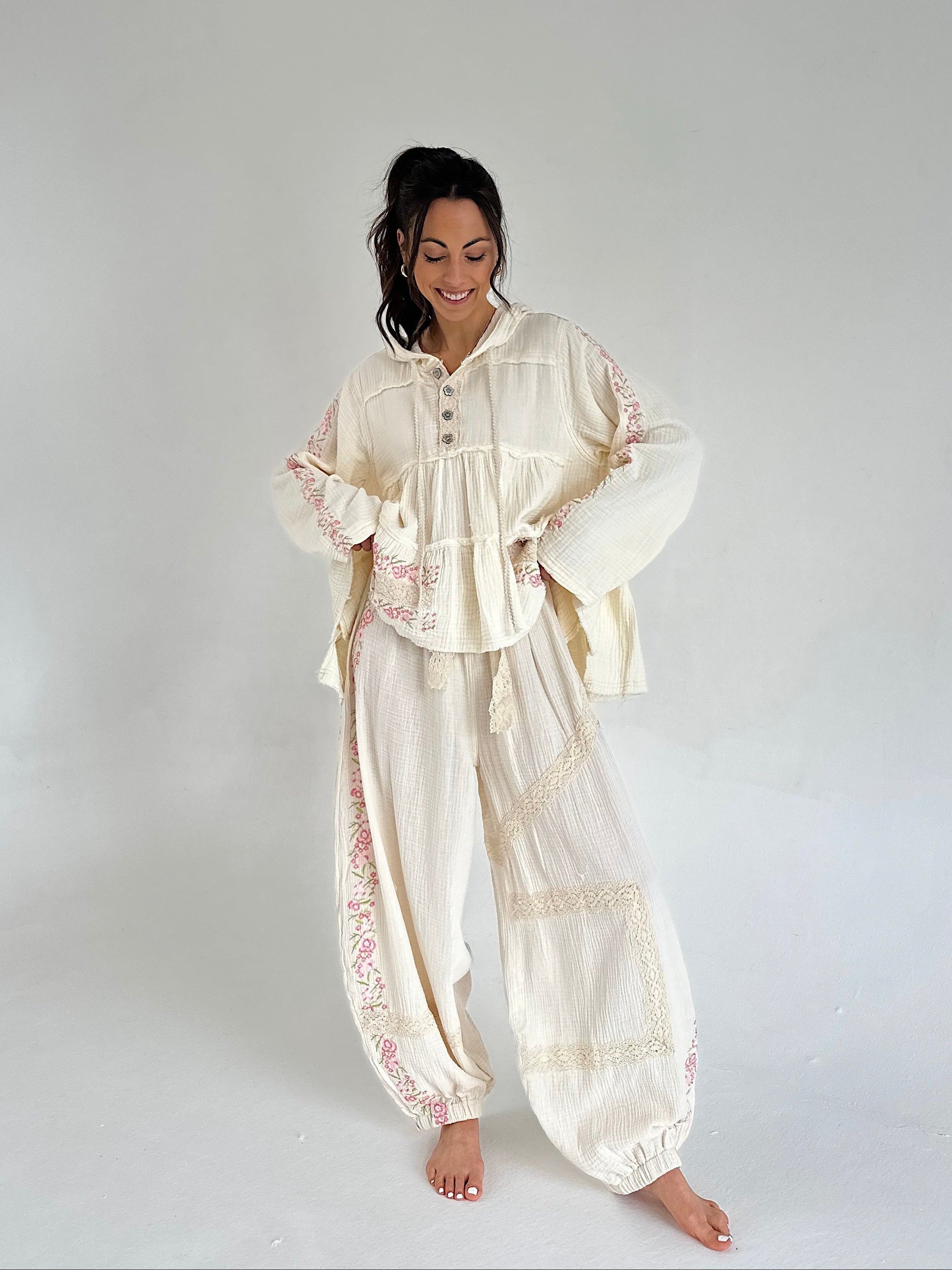 Woman wearing a cream-colored embroidered outfit on a white background